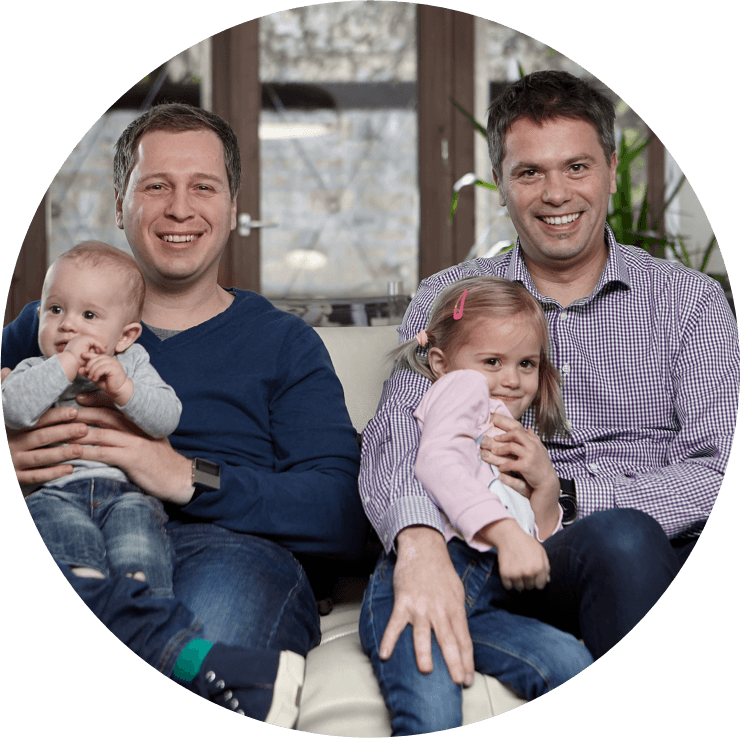 Two fathers, inventors of the Nosiboo products, sitting on a couch with their children and smiling